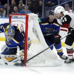 St. Louis Blues goaltender Carter Hutton, left, stops an attempt by Arizona Coyotes' Jordan Martinook, right, as Blues' Vince Dunn watches during the first period of an NHL hockey game Saturday, Jan. 20, 2018, in St. Louis. (AP Photo/Jeff Roberson)