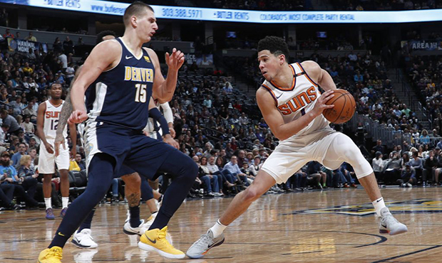 Phoenix Suns guard Devin Booker, right, keeps the ball away from Denver Nuggets center Nikola Jokic...