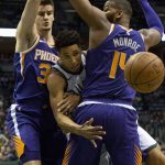 Milwaukee Bucks guard Malcolm Brogdon, center, is defended by Phoenix Suns forward Dragan Bender, left, and Greg Monroe, right, during the first half of an NBA basketball game Monday, Jan. 22, 2018, in Milwaukee. (AP Photo/Darren Hauck)