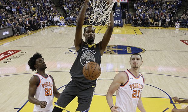 Golden State Warriors' Kevin Durant, center, dunks next to Phoenix Suns' Josh Jackson (20) and Alex...