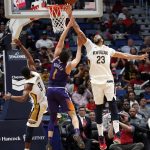 Phoenix Suns guard Devin Booker (1) goes to the basket between New Orleans Pelicans forward Anthony Davis (23) and guard Rajon Rondo (9) in the first half of an NBA basketball game in New Orleans, Monday, Feb. 26, 2018. (AP Photo/Gerald Herbert)