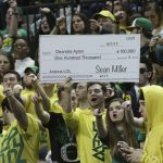 Fans in the Oregon student section hold up a sign making fun of the controversy surrounding Arizona coach Sean Miller, during the first half of an NCAA college basketball game Saturday, Feb. 24, 2018, in Eugene, Ore. (AP photo/Chris Pietsch)