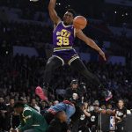 
              Utah Jazz's Donovan Mitchell, top, dunks over three people, including actor Kevin Hart, left, during the NBA All-Star basketball Slam Dunk contest, Saturday, Feb. 17, 2018, in Los Angeles. (AP Photo/Chris Pizzello)
            