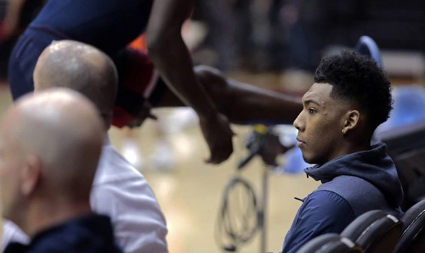 Arizona guard Allonzo Trier, right, sits courtside as teammates warm up before an NCAA college bask...