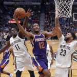 Phoenix Suns forward TJ Warren (12) goes to the basket between New Orleans Pelicans guards Ian Clark (23) and Jrue Holiday (11) in the first half of an NBA basketball game in New Orleans, Monday, Feb. 26, 2018. (AP Photo/Gerald Herbert)