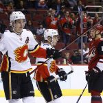 Calgary Flames center Sean Monahan, left, and left wing Johnny Gaudreau, center, celebrate a goal by teammate Sam Bennett as Arizona Coyotes right wing Richard Panik (14) skates past during the first period of an NHL hockey game Thursday, Feb. 22, 2018, in Glendale, Ariz. (AP Photo/Ross D. Franklin)
