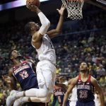 Oregon's MiKyle McIntosh, center, shoots between Arizona's DeAndre Ayton, left, and Keanu Pinder during the first half of an NCAA college basketball game Saturday, Feb. 24, 2018, in Eugene, Ore. (AP photo/Chris Pietsch)