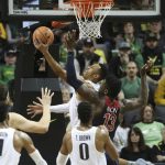Oregon's Elijah Brown, center, shots a reverses layup ahead of Arizona's DeAndre Ayton, right, during the second half of an NCAA college basketball game Saturday, Feb. 24, 2018, in Eugene, Ore. (AP Photo/Chris Pietsch)