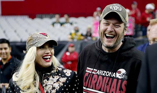 Singers Gwen Stephani and Blake Shelton stand on the sidelines prior to an NFL football game betwee...