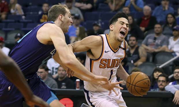 Phoenix Suns guard Devin Booker (1) is fouled by Charlotte Hornets' Cody Zeller as he drives to the...