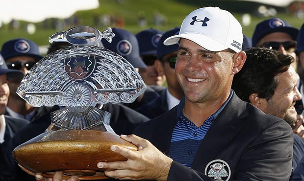Gary Woodland smiles for photographers with the championship trophy after his one-hole playoff win ...