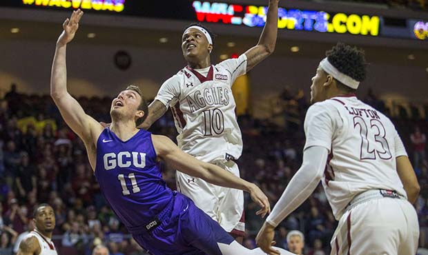 Grand Canyon guard Casey Benson (11) shoots while diving past New Mexico State forward Jemerrio Jon...