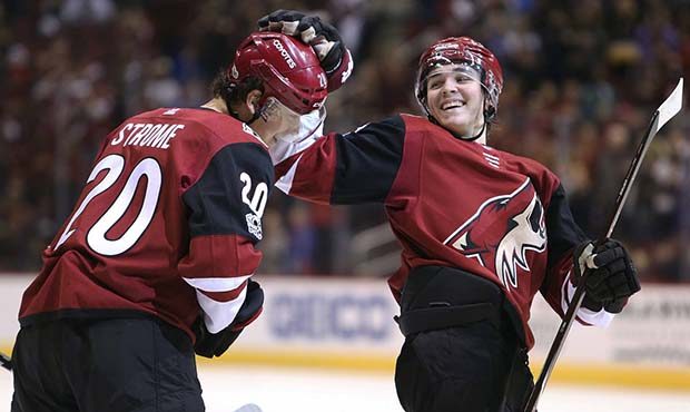 Arizona Coyotes' Dylan Strome (20) gets a pat on the head from teammate Clayton Keller after scorin...