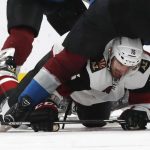 Arizona Coyotes center Brad Richardson, bottom, slides between the legs of Colorado Avalanche center Tyson Jost to reach for the puck in the second period of an NHL hockey game Saturday, March 10, 2018, in Denver. (AP Photo/David Zalubowski)