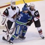 Arizona Coyotes defenseman Jason Demers (55) tries to clear Vancouver Canucks left wing Brendan Leipsic (9) from in front of Coyotes goaltender Darcy Kuemper (35) during the third period of an NHL hockey game Wednesday, March 7, 2018, in Vancouver, British Columbia. (Jonathan Hayward/The Canadian Press via AP)