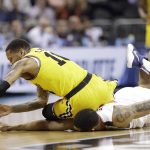 UMBC's Jairus Lyles (10) falls on top of Virginia's Isaiah Wilkins as they chase the ball during the first half of a first-round game in the NCAA men's college basketball tournament in Charlotte, N.C., Friday, March 16, 2018. (AP Photo/Gerry Broome)