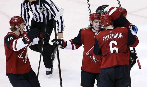 Arizona Coyotes defenseman Kevin Connauton, right, obscured, celebrates his goal against the Minnes...