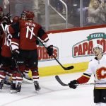 Calgary Flames defenseman Travis Hamonic, right, skates away from the Arizona Coyotes celebration as Coyotes defenseman Niklas Hjalmarsson (4), left wing Max Domi (16), and left wing Brendan Perlini (11) celebrate a goal by Oliver Ekman-Larsson during the third period of an NHL hockey game, Monday, March 19, 2018, in Glendale, Ariz. The Coyotes defeated the Flames 5-2. (AP Photo/Ross D. Franklin)