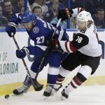 Tampa Bay Lightning defenseman Ryan McDonagh (27) and Arizona Coyotes center Christian Dvorak (18) battle for the puck along the dasher during the first period of an NHL hockey game Monday, March 26, 2018, in Tampa, Fla. (AP Photo/Chris O'Meara)