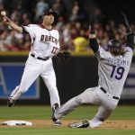 Arizona Diamondbacks' Nick Ahmed (13) throws to first after forcing out Colorado Rockies' Charlie Blackmon (19), for a double play on DJ LeMahieu during the fifth inning of a baseball game Thursday, March 29, 2018, in Phoenix. (AP Photo/Matt York)