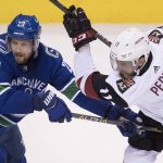 Vancouver Canucks defenseman Alexander Edler (23) fights for control of the puck with Arizona Coyotes left wing Brendan Perlini (11) during the second period of an NHL hockey game Wednesday, March 7, 2018, in Vancouver, British Columbia. (Jonathan Hayward/The Canadian Press via AP)
