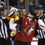 Arizona Coyotes defenseman Oliver Ekman-Larsson, center, reacts after getting hit on the face by referee TJ Luxmore (21) as Luxmore calls a penalty on him during the first period of an NHL hockey game Thursday, March 15, 2018, in Glendale, Ariz. Linesman Shane Heyer, right, skates near the action. (AP Photo/Ross D. Franklin)