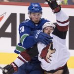 Vancouver Canucks right wing Jake Virtanen (18) and Arizona Coyotes left wing Jordan Martinook (48) jump to reach the puck during the third period of an NHL hockey game Wednesday, March 7, 2018, in Vancouver, British Columbia. (Jonathan Hayward/The Canadian Press via AP)