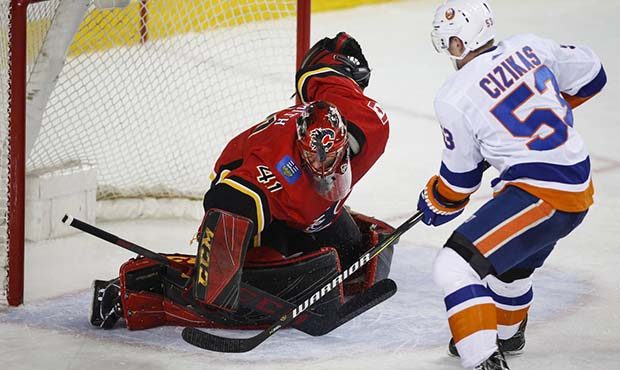 New York Islanders' Casey Cizikas, right, has his shot deflected by Calgary Flames goalie Mike Smit...