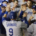 Los Angeles Dodgers' Yasmani Grandal (9) celebrates his run scored against the Arizona Diamondbacks with teammates and coaches in the dugout during the eighth inning of a baseball game Monday, April 30, 2018, in Phoenix. Arizona won 8-5. (AP Photo/Ross D. Franklin)