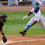 Los Angeles Dodgers' Yasiel Puig, right, scores on a sacrifice fly hit by Enrique Hernandez as Arizona Diamondbacks catcher Jeff Mathis, left, awaits a late throw during the second inning of a baseball game Sunday, April 15, 2018, in Los Angeles. (AP Photo/Mark J. Terrill)