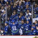 Vancouver Canucks' Henrik Sedin (33) and his twin brother, Daniel Sedin, right, both of Sweden, acknowledge a standing ovation during the first period of the team's NHL hockey game against the Arizona Coyotes on Thursday, April 5, 2018, in Vancouver, British Columbia. (Darryl Dyck/The Canadian Press via AP)