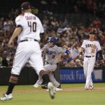 Los Angeles Dodgers' Yasmani Grandal (9) scores on a base hit by Cody Bellinger during the sixth inning of a baseball game as Arizona Diamondbacks relief pitcher Andrew Chafin (40) and Jake Lamb (22) look on, Monday, April 2, 2018, in Phoenix. (AP Photo/Matt York)