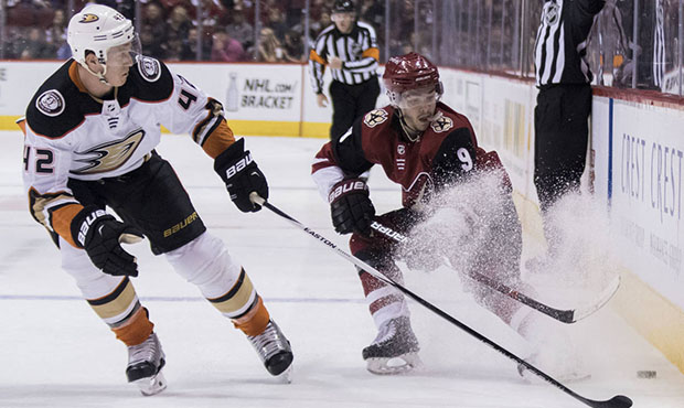 Phoenix Coyotes' Clayton Keller, right, throws up some ice as he protects the puck from Anaheim Duc...