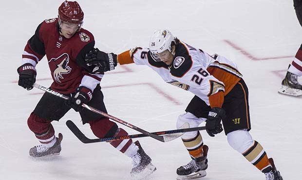 Phoenix Coyotes' Max Domi, left, gets shoved away from the puck by the Anaheim Ducks' Brandon Monto...