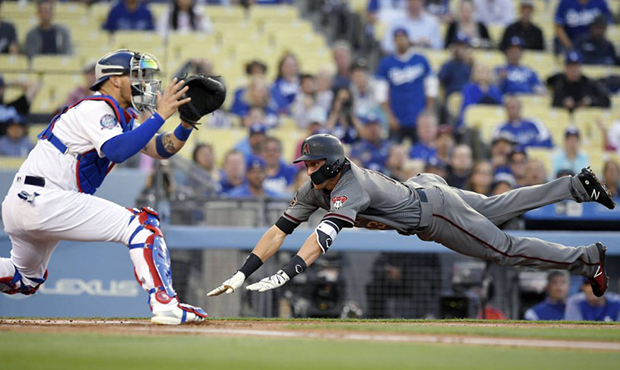 Arizona Diamondbacks' Nick Ahmed, right, dives in ahead of the tag of Los Angeles Dodgers catcher Y...