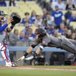 Arizona Diamondbacks' Nick Ahmed, right, dives in ahead of the tag of Los Angeles Dodgers catcher Yasmani Grandal on an inside-the-park home run during the first inning of a baseball game Wednesday, May 9, 2018, in Los Angeles. (AP Photo/Mark J. Terrill)