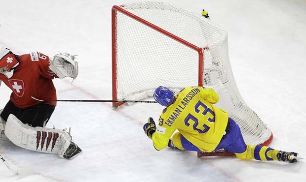 Sweden's Oliver Ekman-Larsson, right, tries to score, to Switzerland's goalie Leonardo Genoni durin...