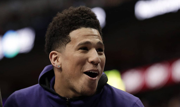 Phoenix Suns guard Devin Booker laughs with teammates on the bench after a score against the Dallas...