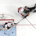 Vegas Golden Knights left wing William Carrier, right, falls as he tries to shoot while under pressure from Washington Capitals defenseman Christian Djoos, center, while Capitals goaltender Braden Holtby sits in goal during the first period in Game 5 of the NHL hockey Stanley Cup Finals Thursday, June 7, 2018, in Las Vegas. (AP Photo/John Locher)