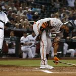 San Francisco Giants' Andrew McCutchen, right, places his bat on the ground after striking out, while Arizona Diamondbacks catcher Jeff Mathis, left, heads back to the dugout during the first inning of a baseball game Friday, June 29, 2018, in Phoenix. (AP Photo/Ross D. Franklin)