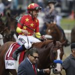 Jockey Mike Smith rides Justify to the winner's circle led by assistant trainer Jimmy Barnes, left, and Carlos Martin after winning the 150th running of the Belmont Stakes horse race and the Triple Crown, Saturday, June 9, 2018, in Elmont, N.Y. (AP Photo/Julio Cortez)
