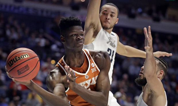 Texas forward Mohamed Bamba passes under pressure from Nevada guard Kendall Stephens (21) and forwa...