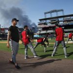 A pillar of smoke builds in the background from a fire in a recycling plant near Coors Field as Arizona Diamondbacks second baseman Ketel Marte warms up before the team's baseball game against the Colorado Rockies on Tuesday, July 10, 2018, in Denver. (AP Photo/David Zalubowski)