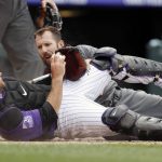 Colorado Rockies catcher Chris Iannetta, front, holds up the ball to show Arizona Diamondbacks' Steven Souza Jr. that he was tagged out at home plate while trying to advance from third base on a ground ball hit by catcher John Ryan Murphy in the sixth inning of a baseball game Thursday, July 12, 2018, in Denver. (AP Photo/David Zalubowski)