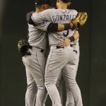 Colorado Rockies outfielders Gerardo Parra, left, Carlos Gonzalez, center, and Charlie Blackmon, hidden, hug it out after their 11-10 victory over the Arizona Diamondbacks during a baseball game Friday, July 20, 2018, in Phoenix. (AP Photo/Darryl Webb)