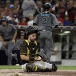 San Diego Padres catcher Austin Hedges, bottom, looks on after Arizona Diamondbacks' Jeff Mathis, top, scored from second base off an RBI-single by Jon Jay during the third inning of a baseball game Friday, July 27, 2018, in San Diego. (AP Photo/Gregory Bull)