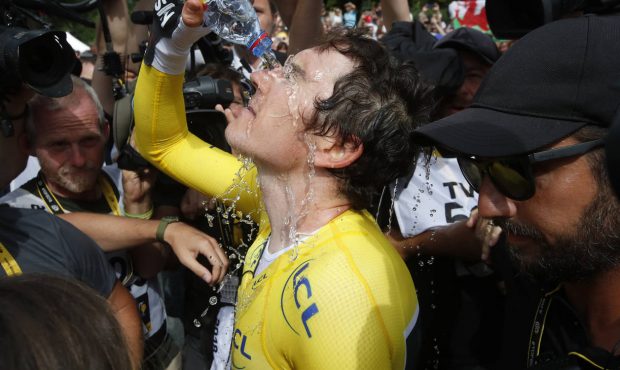 Britain's Geraint Thomas, wearing the overall leader's yellow jersey, pours water over his face aft...