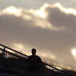 A lone fan is silhouetted in the club level of Coors Field as the setting sun illuminates a bank of clouds as the Colorado Rockies bat against the Arizona Diamondbacks in the third inning of a baseball game Wednesday, July 11, 2018, in Denver. (AP Photo/David Zalubowski)