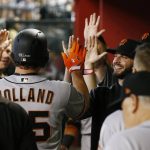 San Francisco Giants ' Derek Holland, left, celebrates his run scored against the Arizona Diamondbacks with teammates, including Andrew Suarez, right, during the fourth inning of a baseball game Sunday, July 1, 2018, in Phoenix. (AP Photo/Ross D. Franklin)