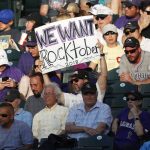 A Colorado Rockies fan holds up a placard with hopes for a post-season appearance by the team, which was playing the Arizona Diamondbacks during the third inning of a baseball game Tuesday, July 10, 2018, in Denver. (AP Photo/David Zalubowski)